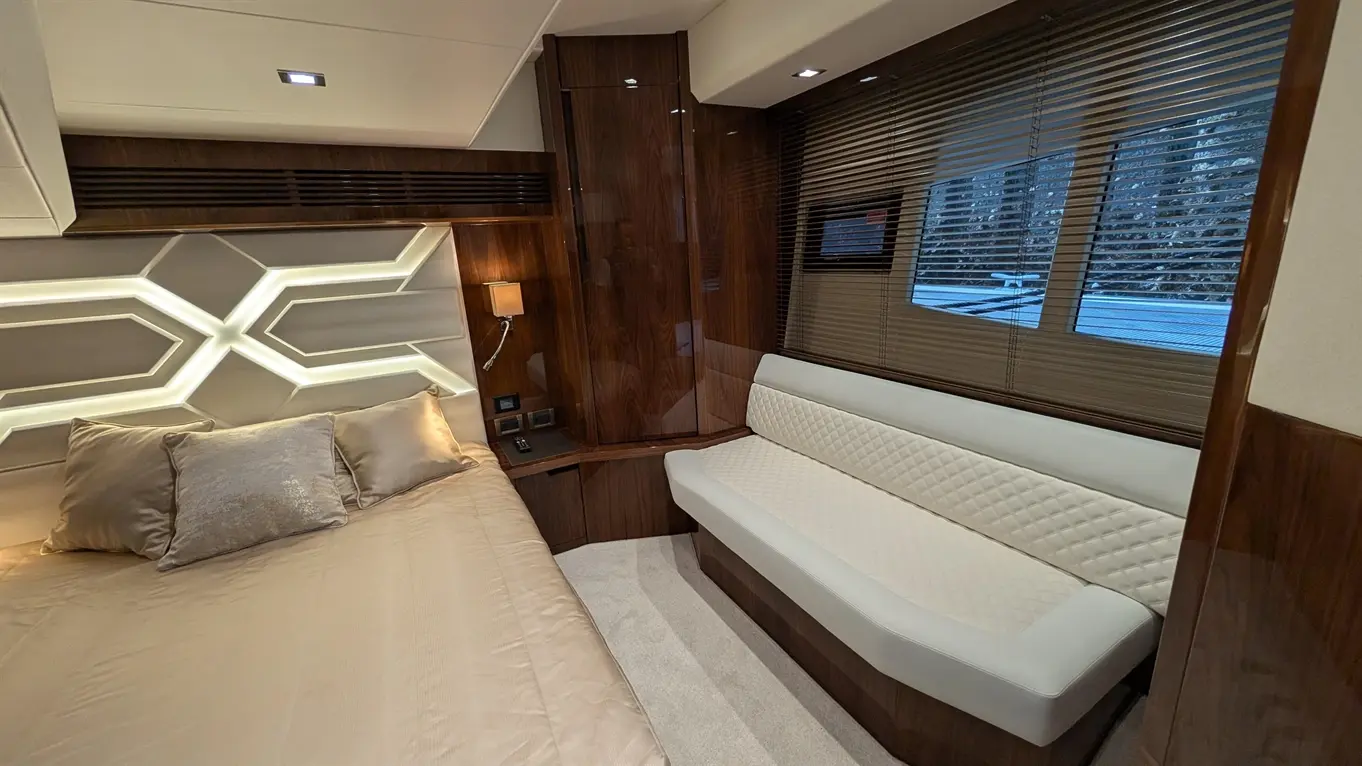 Luxury cabin featuring a plush bed with decorative pillows, modern seating, ambient lighting, and large windows with blinds.